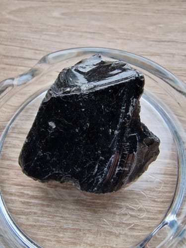 Avis d'un client : une pierre d'obsidienne noire brute et brillante posée dans une coupelle en verre.