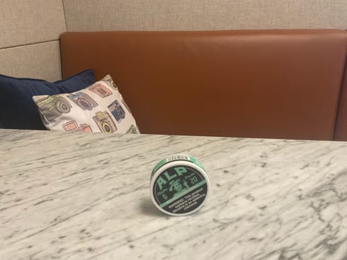 Reviewer's can of Refreshing Chill Nicotine Pouches sitting on a marble table.