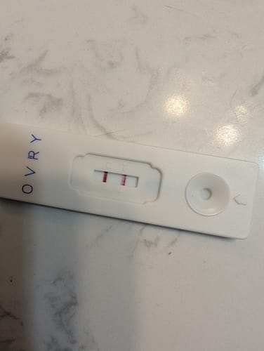 Customer's Ovry Male Fertility Test on a marble surface, showing a positive result with two red lines.