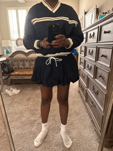 Reviewer taking a mirror selfie wearing the navy V-Neck Overhead Shirt with cream trim and a matching skirt.