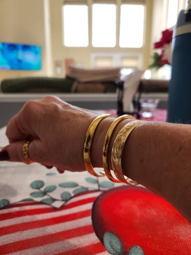 Reviewer showing a stack of three gold Marbella Cuff Bracelets on their wrist.