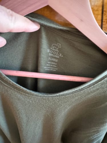 Close-up: Customer showing the printed X-Large tag inside the green Explorer Base Layer shirt.