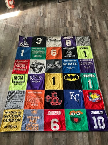 Customer's colorful Premium T Shirt Quilt made from their son's childhood shirts, featuring sports and character designs.