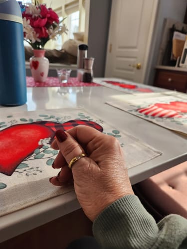 Reviewer's hand wearing the gold Treasure Birthstone Ring while resting on a placemat at a table.