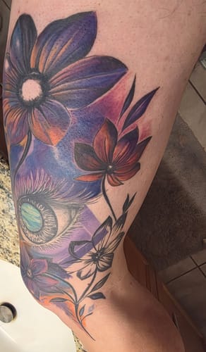 Reviewer's large, colorful floral tattoo on their leg, completed using Painless Tattoo Numbing Cream.