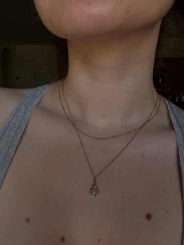 Customer shows a close-up of the yellow gold Niyah Bead Chain Necklace layered on their neck.