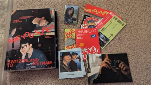 Customer's 'Are You Sure?! Season 2' photobook and included gifts, such as photocards and stickers, laid out on a carpet.