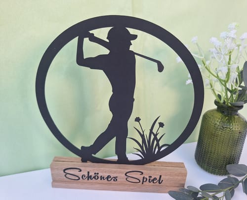 Kunde zeigt einen Easy-Stick mit der Aufschrift 'Schönes Spiel', der als Halterung für einen schwarzen Scherenschnitt eines Golfers dient.