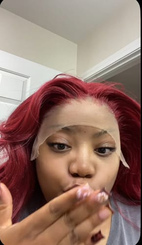 Customer wearing the vibrant red Outre Elara wig with its uncut HD lace, blowing a kiss to the camera.