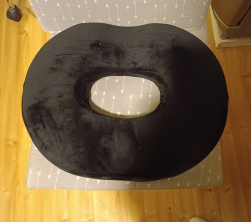 A vásárló fekete, memóriahabos prosztata párnája egy mintás széken, felülnézetből.