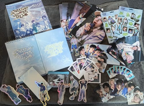Customer displays all contents of the Stray Kids Starlight Supper Club Season's Greetings, including photocards and books.