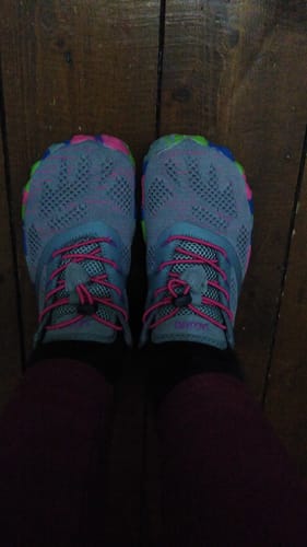 Customer wearing colorful Smart II Barefoot Shoes with pink laces on a wooden floor.