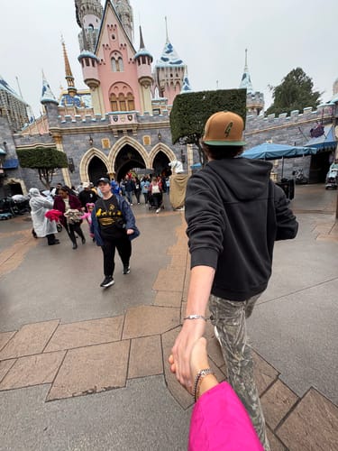 Customer and a partner holding hands, both wearing matching Engravable Cuban Link Bracelets at a theme park.