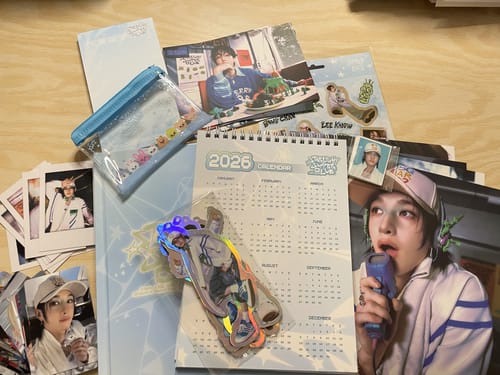 Customer's STRAY KIDS 2026 SEASON'S GREETINGS items spread out, showing a desk calendar, photocards, and a small clear pouch.