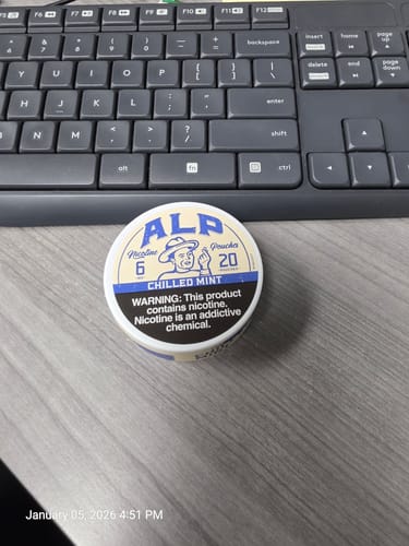 Customer's tin of ALP Chilled Mint Nicotine Pouches on a grey desk by a keyboard.