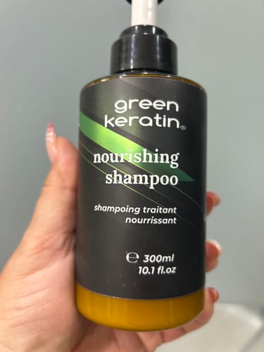 Un client tenant la bouteille noire du Shampoing nourrissant Green Keratin dans sa main.