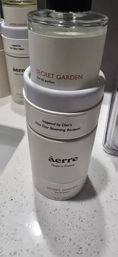 Customer's bottle of Secret Garden perfume sitting inside its white cylindrical packaging.