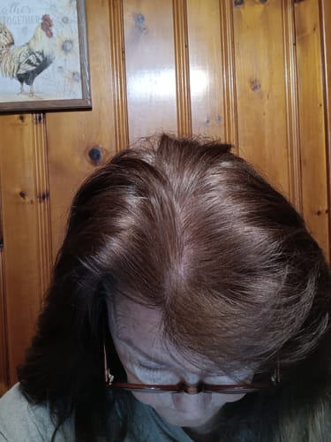 Close-up of a reviewer's hair after using the dye, showing the reddish-brown result at the roots.