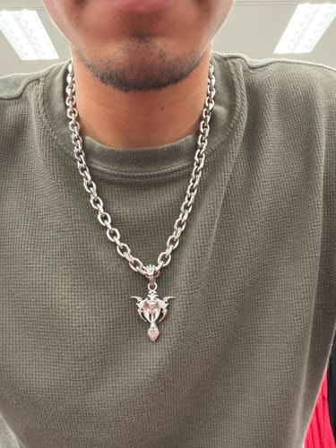 Customer wearing the 8MM Mini Aries Chain, a thick silver necklace, with an intricate cross pendant.