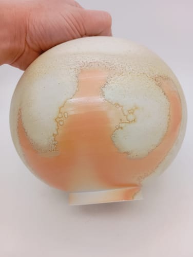 Reviewer's hand holding a glazed pot with a smooth base finished using the sanding disc.