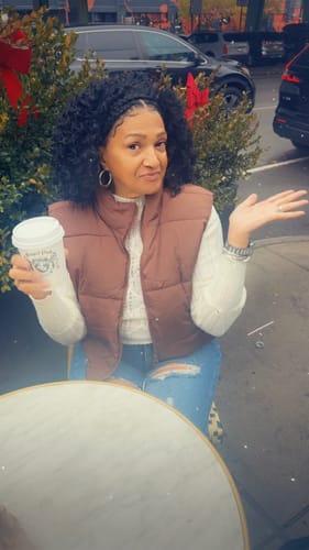 Customer outdoors wearing the Outre Halo Stitch Braid wig. The black, pre-styled wig has kinky curls and a braided halo.