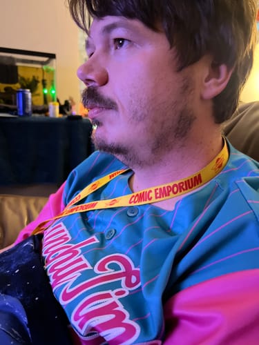 Close-up of a reviewer wearing the custom aqua and pink striped baseball jersey indoors.