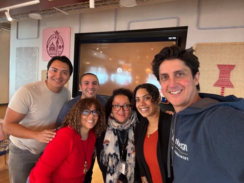 Reviewer wearing the vibrant red Beck Fitted Crewneck Sweater while in a group photo indoors.