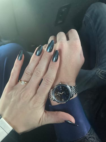 Customer's photo of a person wearing a silver-toned watch with a dark face while holding hands.