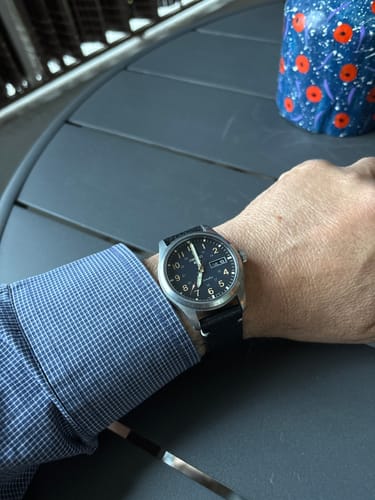 Reseñador mostrando el reloj Seiko 5 en su muñeca, con una elegante correa de cuero negra y esfera oscura.