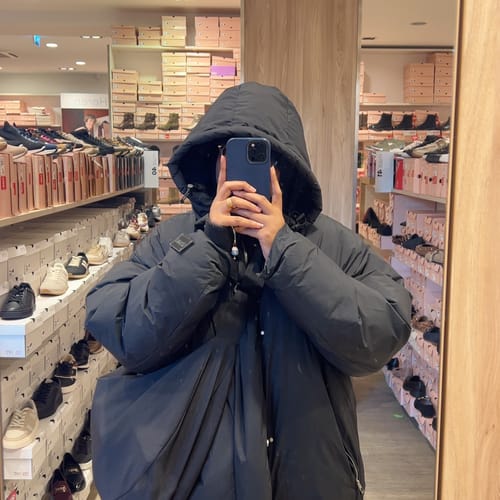 Reviewer showing the navy blue SIV bag styled with a puffy coat in a store mirror selfie.