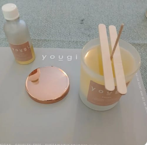 Customer's handmade candle from the workshop, setting in a jar next to the fragrance oil and a rose gold lid.