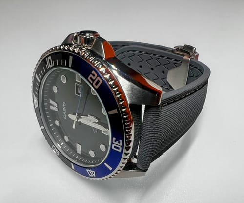 Reviewer's gray Sailcloth Rubber Deploy strap on a dive watch, showing its textured finish and deployment clasp.