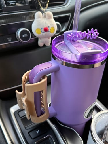 Customer's beige cloud clip attached to the handle of a purple tumbler inside a car.