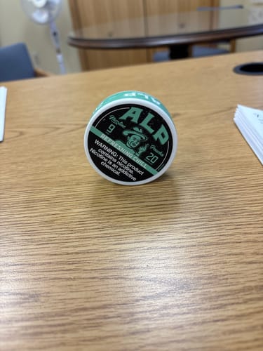 Customer's can of Refreshing Chill Nicotine Pouches sitting on a wooden desk.
