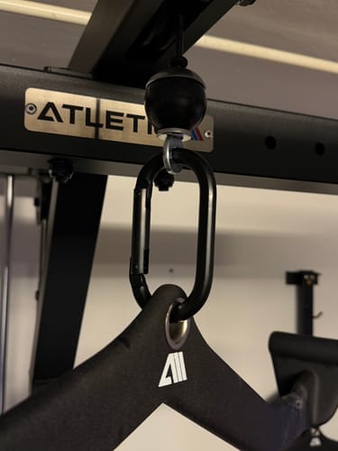 Ein Kunde zeigt den schwarzen Karabinerhaken, der einen Griff mit einer Kabelzugmaschine verbindet.