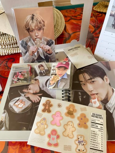 Customer photo showing the ATEEZ 2026 Season's Greetings contents, including photocards, a calendar, and cute gingerbread stickers.