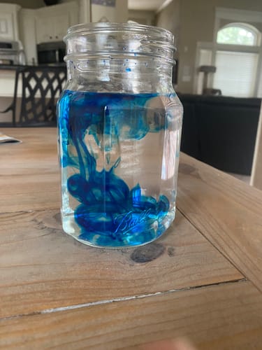 Customer showing Meraki Blu Methylene Blue dye swirling in a glass jar of liquid.
