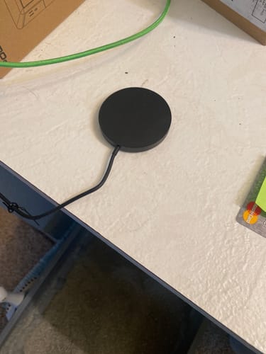 Customer's black, circular wireless charger shown on a desk.