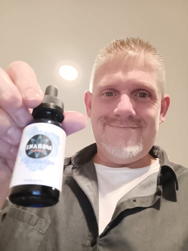 Customer holding a blue dropper bottle of Meraki Blu Methylene Blue toward the camera.