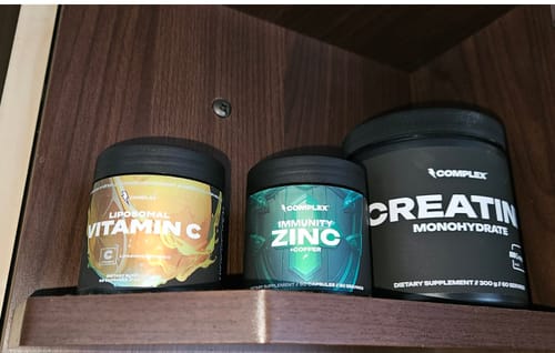 Customer's tub of Complex Immunity Zinc next to other Complex supplements on a wooden shelf.