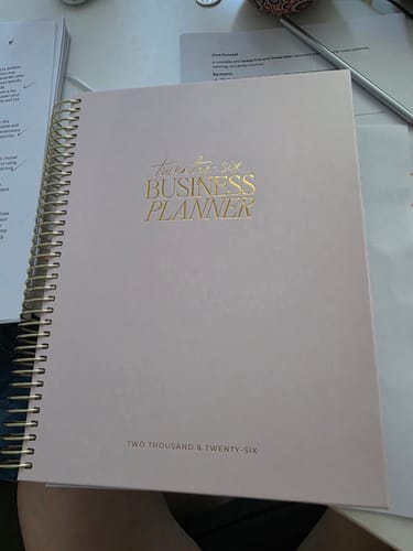 Reviewer's blush 2026 Business Planner with gold spiral binding and gold foil text.