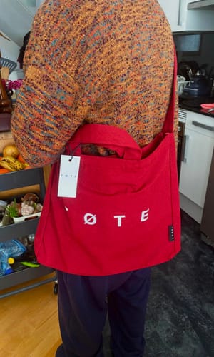 Reviewer wearing the Burgundy Red TØTE Bag cross-body with the tag still attached.