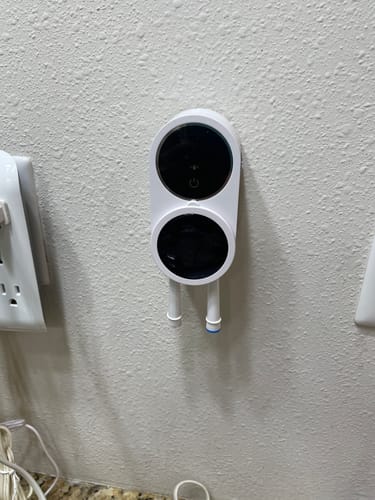 Customer's white UV Toothbrush Sterilisation unit mounted on a wall, holding two toothbrushes.