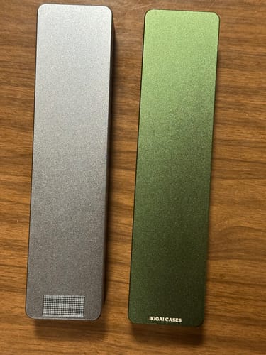 Reviewer's two sturdy metal pill cases, one silver and one green, from the 2-pack bundle shown closed on a table.