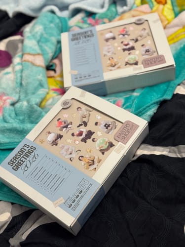 Customer's two packaged ATEEZ - 2026 SEASON'S GREETINGS boxes resting on a bed.