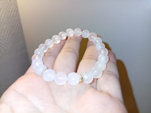 Un client tient le Bracelet Pierre de Lune et Quartz Rose dans la paume de sa main.