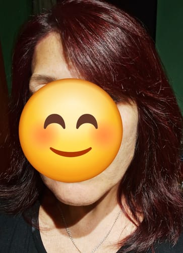Una cliente muestra su cabello rojizo y suave después de usar el Acondicionador Antifrizz.