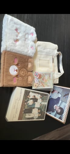 Reviewer's brown MOCHA BEAR PLUSH BINDER displayed with another plush item, a tote bag, and K-pop merchandise.
