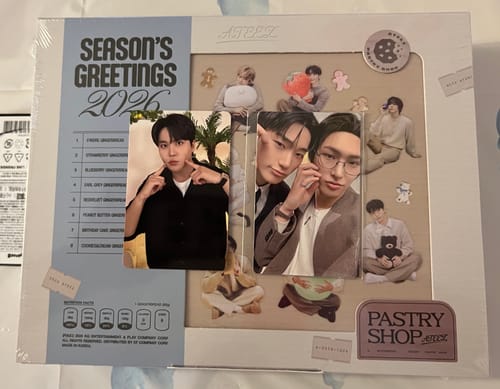 Customer shows the ATEEZ 2026 SEASON'S GREETINGS box in its packaging with two photocards displayed on top.