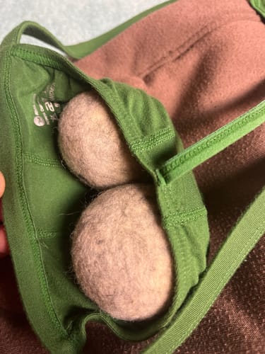 Close-up of a reviewer showing the green Modal Thong's pouch holding two round objects to demonstrate the fit.